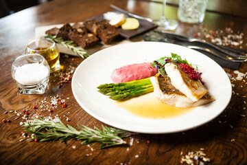 Pike-perch fillet. Asparagus, pearl couscous, white wine sauce, beet-flavored mashed potatoes. Delicious seafood fish closeup served on a table for lunch in modern cuisine gourmet restaurant