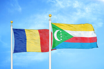 Romania and Comoros two flags on flagpoles and blue sky