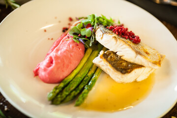 Pike-perch fillet. Asparagus, pearl couscous, white wine sauce, beet-flavored mashed potatoes. Delicious seafood fish closeup served on a table for lunch in modern cuisine gourmet restaurant