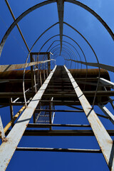 Iron staircase to the water tower against the background of a clear summer sky.