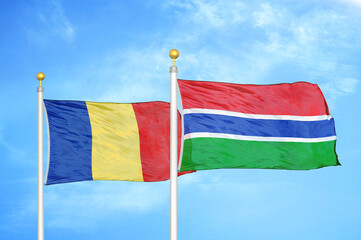 Romania and Gambia two flags on flagpoles and blue sky