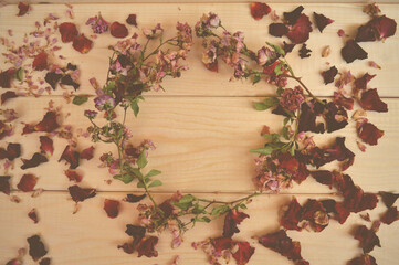 A wreath of dried dews on a background of wood around rose petals. Antique photo