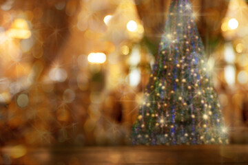 Abstract Christmas blurred bokeh background with rustic wood table in front of Christmas tree.