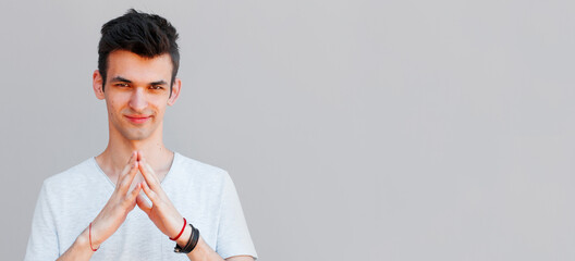 Studio closeup shot of sneaky sly and scheming young European man dressed in grey t-shirt looking...