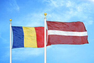 Romania and Latvia two flags on flagpoles and blue sky