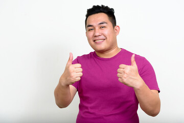 Portrait of happy young handsome overweight Asian man