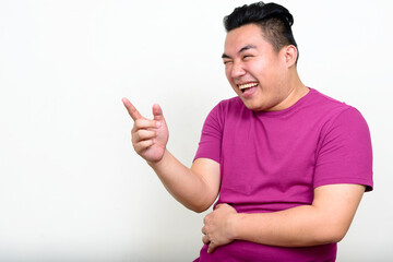 Portrait of happy young handsome overweight Asian man
