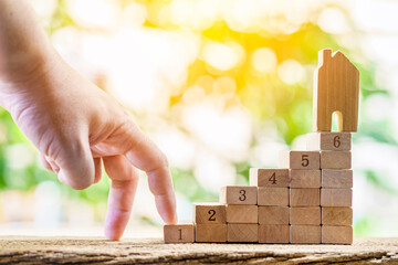 Close up of hand with climb up on a stacking six wooden sticks with growing on by steps and home is...