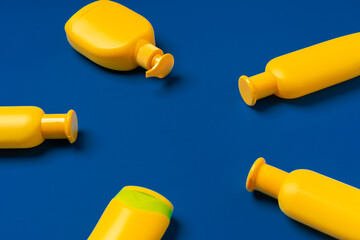 Bright yellow bottles of sunscreen product on dark blue paper background