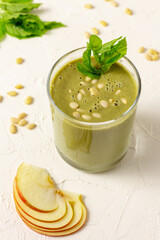 Blended green fruit smoothie in glass with pine nuts