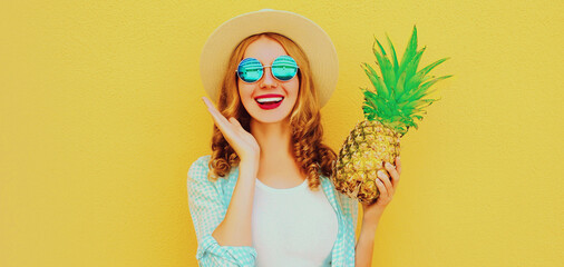 Summer portrait happy smiling woman with pineapple having fun wearing a straw hat, sunglasses over colorful yellow background