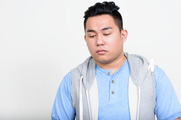 Portrait of stressed young overweight Asian man thinking