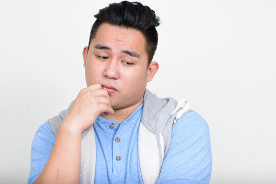 Portrait of stressed young overweight Asian man thinking