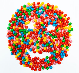 jelly beans forming a drawing of a face of various colors with a white background