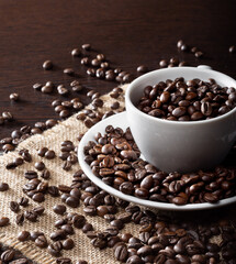 Roasted coffee beans in a white Cup on a wooden table. Coffee beans on burlap.