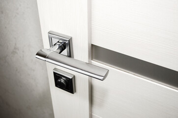 Metal door handle close-up. Interior door with glass inserts