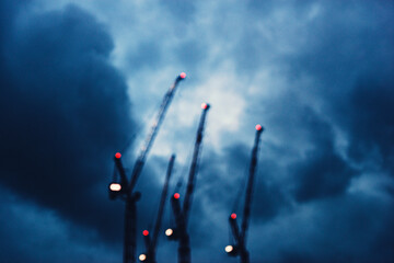 Tres grúas de construcción desenfocadas con cielo azul nublado con contraste