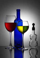 Stylish, modern still life with a bottle and two glasses filled with colored liquid and a violin-shaped glass container.