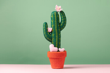 A toy felt blooming cactus with cute small hearts are on a light green background. Concept wedding...