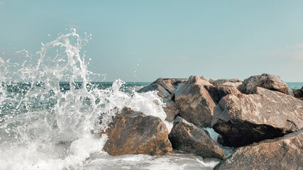 Seascape of rocky beach. Sea waves crash and splash on rocks. View of the sea, ocean. Natural soft blue background. View of the sea, ocean. Rockaway Beach,