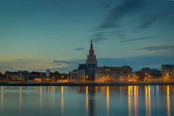 Fototapeta premium Night view on the illuminated riverside with reflection on the river in Riga