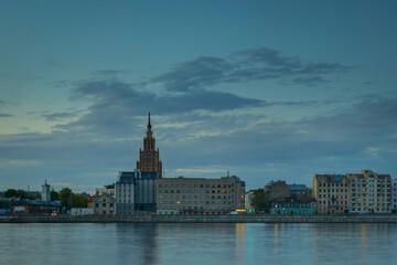 Night view on the illuminated riverside with reflection on the river in Riga