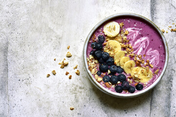 Blueberry banana smoothie with granola in a bowl. Top view with copy space.