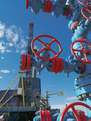 Fountain fittings of a gas well with high-pressure gate valve handwheels. The drilling rig is in...