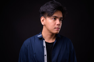 Obraz premium Young handsome Asian man against black background