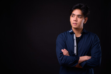 Young handsome Asian man against black background