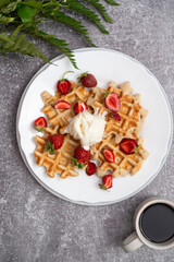 Viennese waffles with ice-cream and strawberries with cup of coffee. Top view. Grey background.