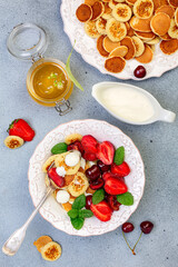 Porridge of tiny pancakes with berries, cream and honey.