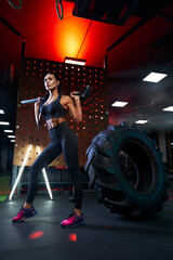 Fototapeta na wymiar Gorgeous brunette woman posing with sledgehammer in gym.