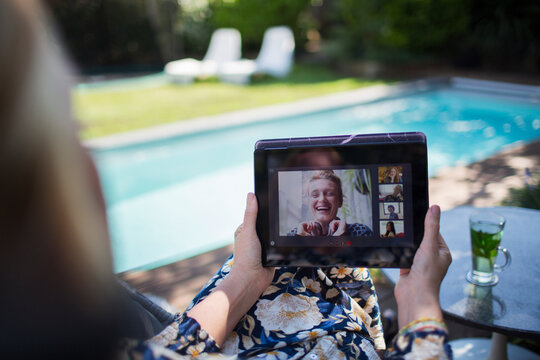 Woman video chatting with friends on digital tablet at poolside