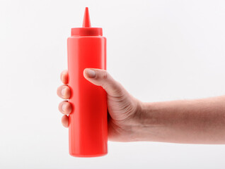 Hand holding a red squeeze bottle, isolated on white background