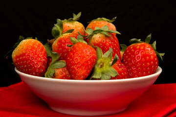 Red fresh strawberry in a bowl on black background.