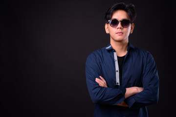 Young handsome Asian man against black background