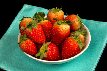 Red fresh strawberry in a bowl on black background.