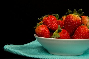 Red fresh strawberry in a bowl on black background.