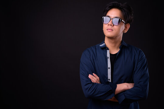 Young handsome Asian man against black background