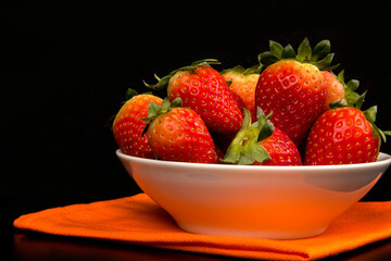 Red fresh strawberry in a bowl on black background.