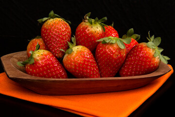 Red fresh strawberry in a bowl on black background.