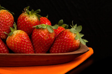 Red fresh strawberry in a bowl on black background.