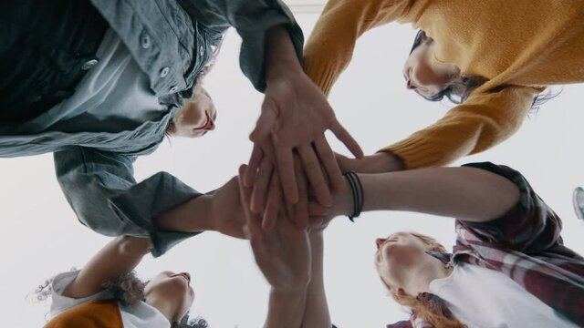 Group of female friends stacking hands in a huddle. Multiracials girls enjoying outdoors.
