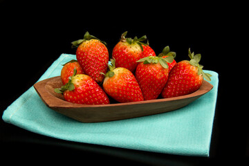 Red fresh strawberry in a bowl on black background.