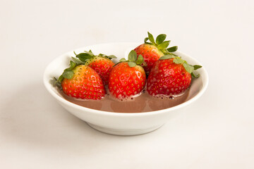 Fresh red strawberries in a bowl with chocolate cream.