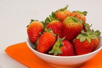 Red fresh strawberry in a bowl on white background.