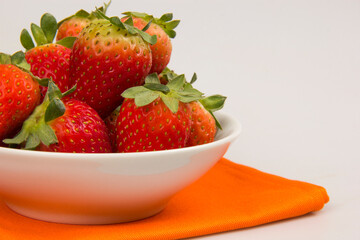 Red fresh strawberry in a bowl on white background.