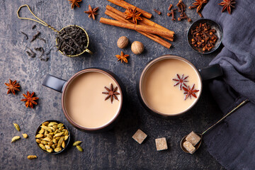 Indian masala tea with milk and spices in mug. Grey background. Top view.