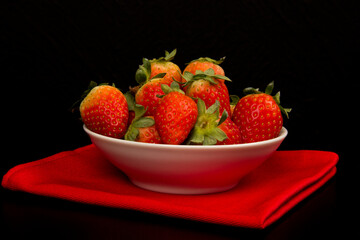 Red fresh strawberry in a bowl on black background.